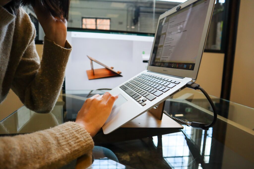 Bilden visar en person som arbetar med en laptop. En KVM switch kan underlätta ergonomin när du använder flera olika datorer.